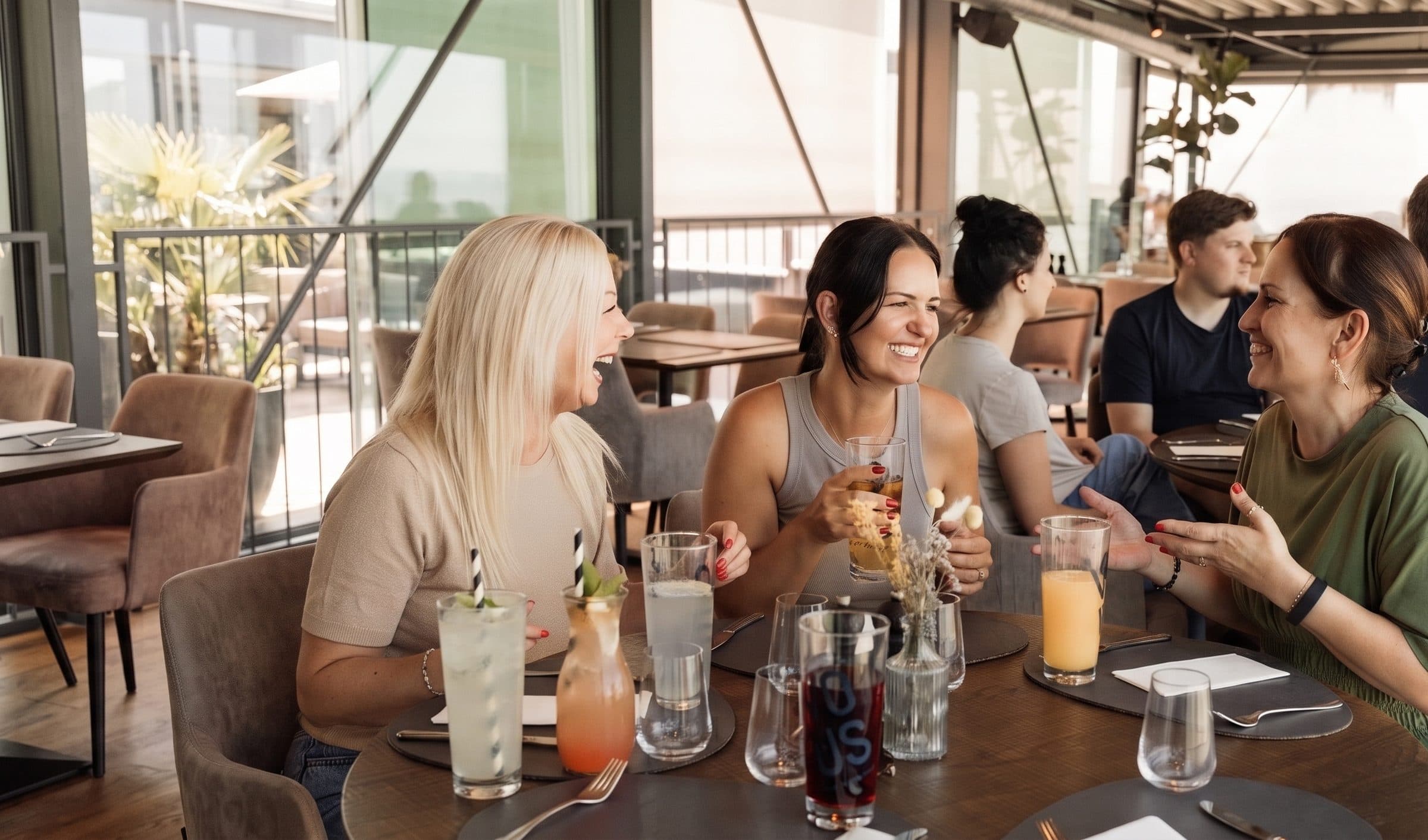 Kolleginnen lachen beim gemeinsamen Mittagessen im Lokal