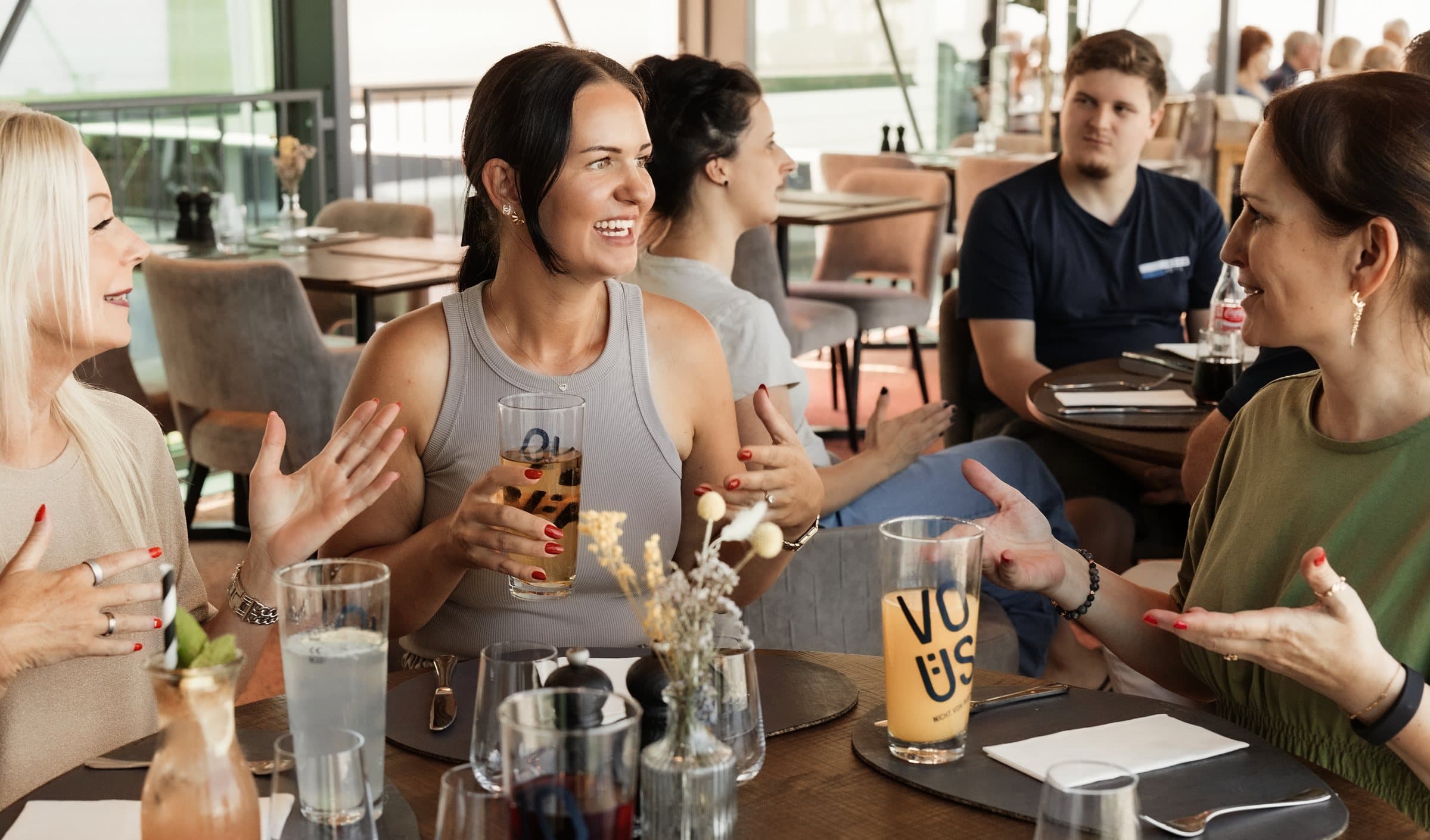 Kolleginnen lachen beim gemeinsamen Mittagessen im Lokal