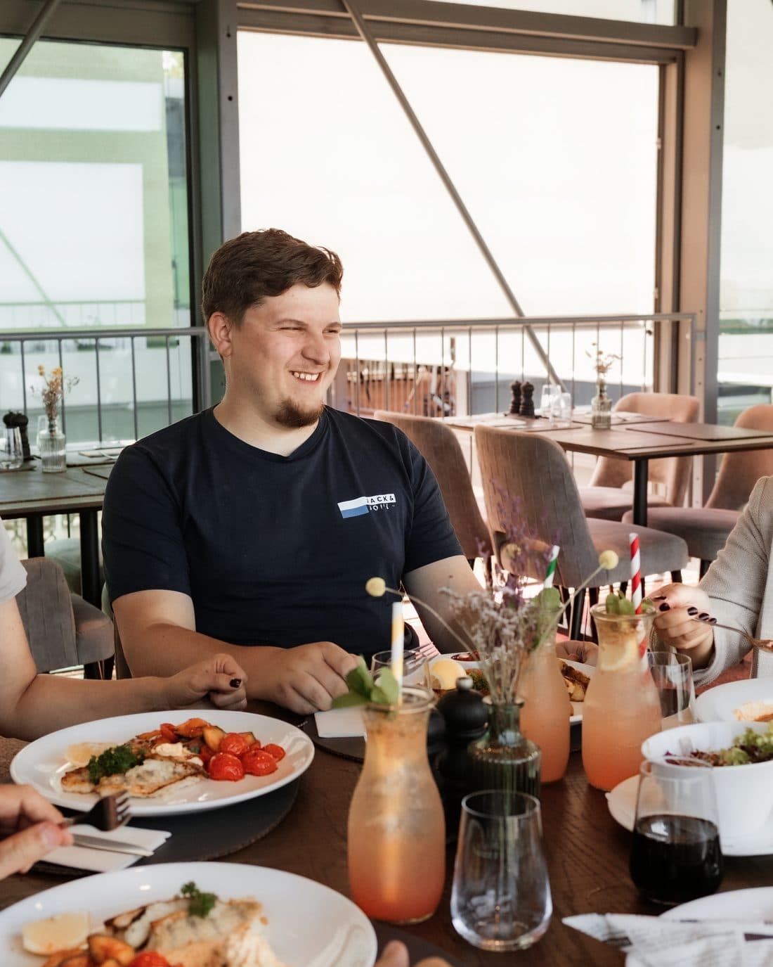 Mittagstisch im Lokal: Teller mit warmem Essen, Gäste im Gespräch