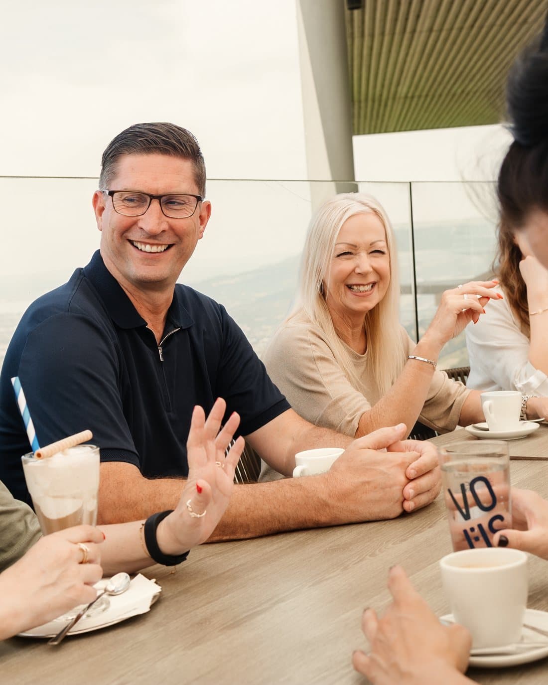 Kolleginnen und Kollegen lachen bei der Mittagspause auf der Terrasse